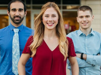 One woman and four men standing in a line smiling