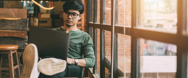 guy in green shirt with legs up on chair working on laptop
