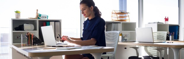 woman wearing black top sitting at desk working on laptop