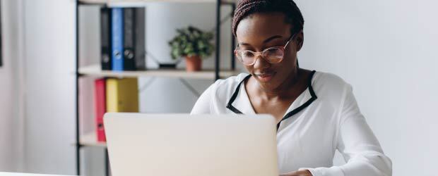focused woman sitting at desk using laptop