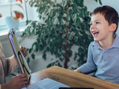 Teacher helping a smiling student learn the alphabet.