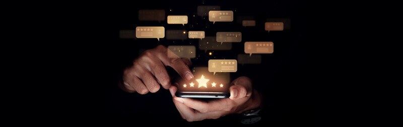 Hand of man using smartphone with five star review for a brand