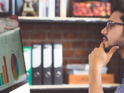 man sitting at desk looking at metrics on screen