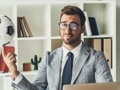A young business sports agent spinning a soccer ball on his finger at the workplace.