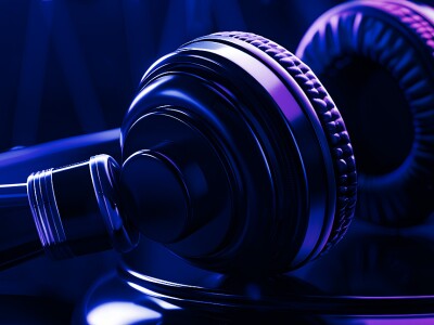 Close-up of a gavel and a pair of headphones illuminated by purple and blue lights