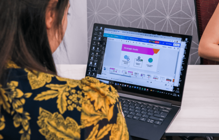 Woman seated at table looking at online course on laptop screen