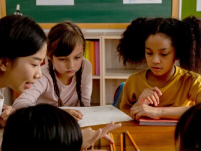 woman-teaching-five-kids-green-chalkboard-in-background