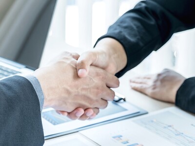 Two people shaking hands across a table