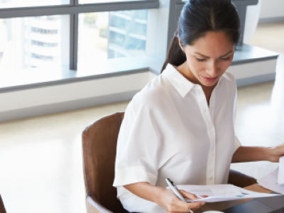 woman-in-white-blouse-sitting-looking-at-papers-on-her-lap