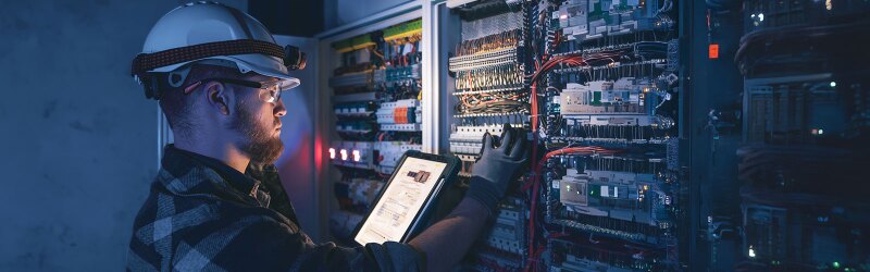 Electrical engineer wearing goggles and hardhat working on servers