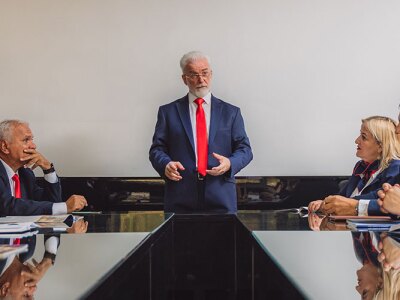 Senior business people discussing at modern office meeting room. 70s company leader talking to his employees.