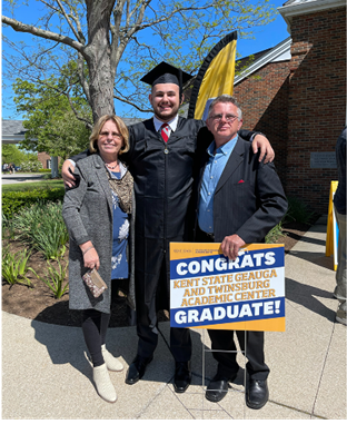Alan T. in cap and gown with parents celebrating his graduation
