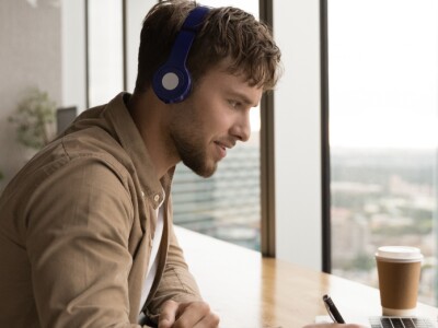 Man wearing headphones using laptop, studying online
