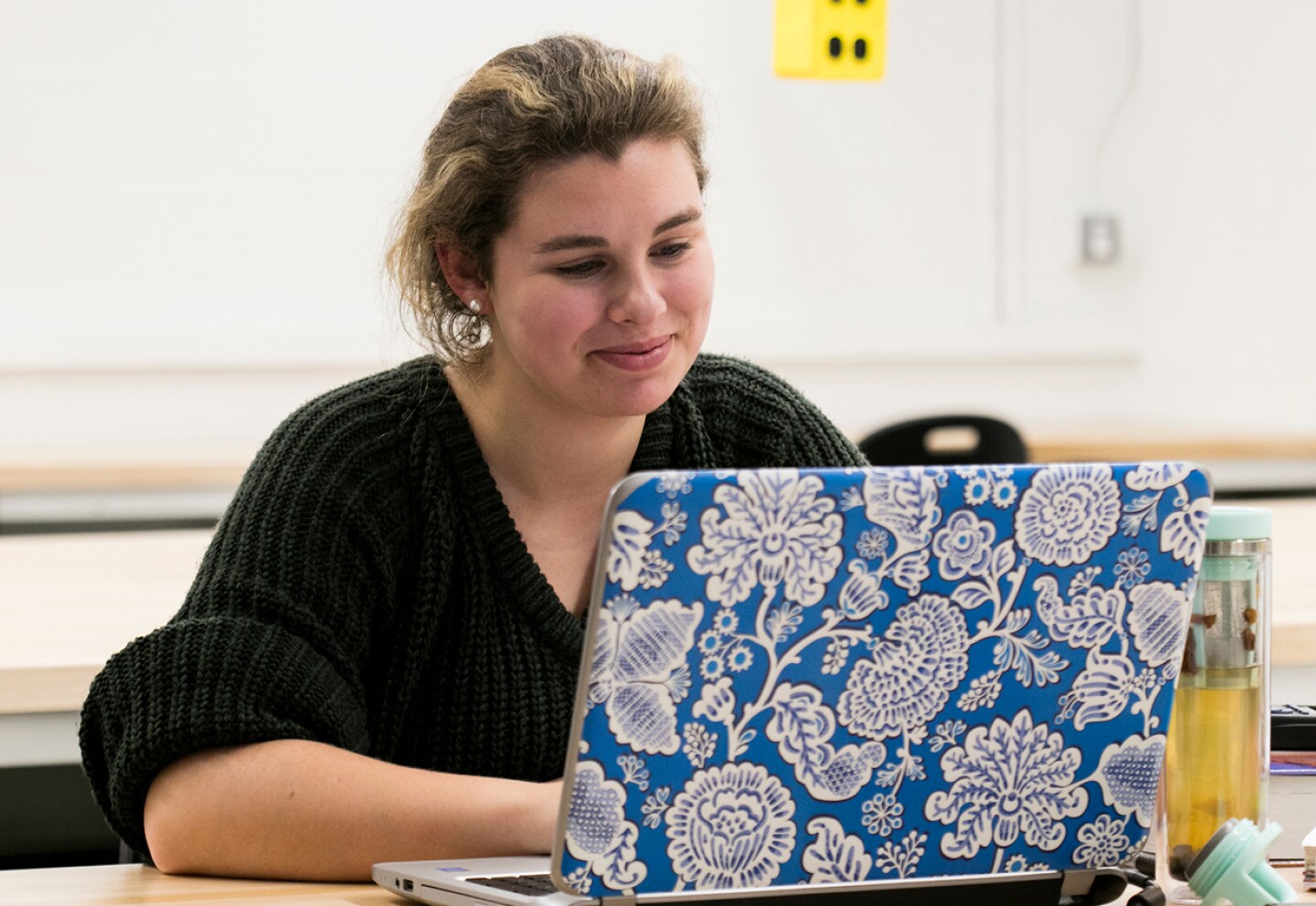 Smiling female student working on her laptop