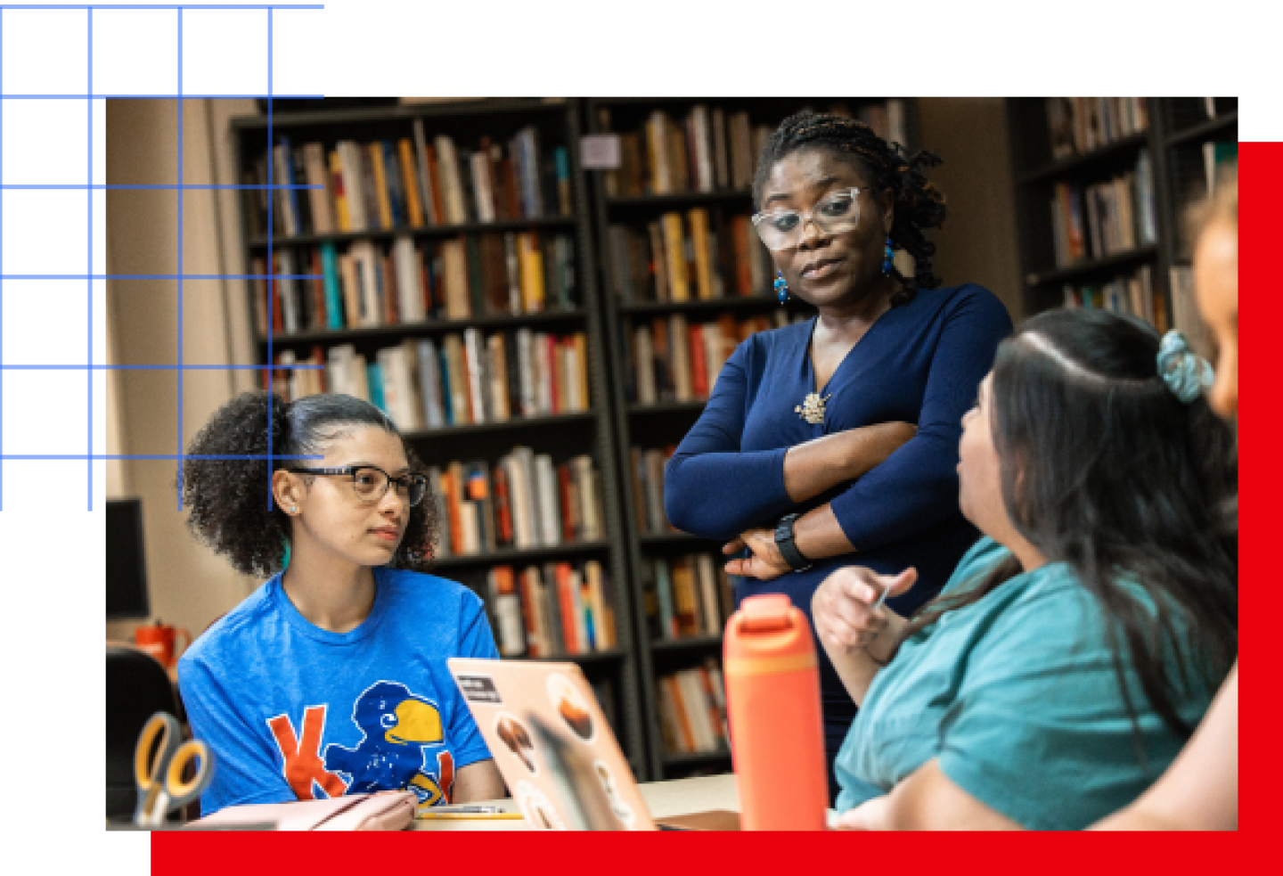 A female KU professor stands with arms crossed while talking with two female KU students.