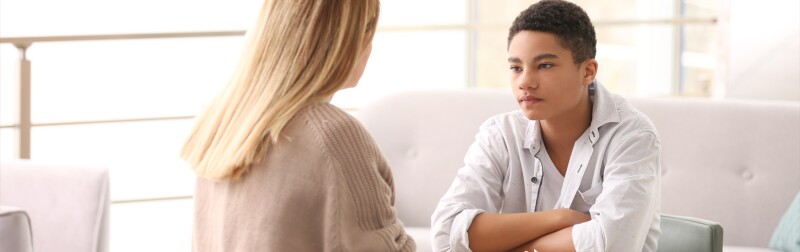 Young female counselor working with teenage boy in office.