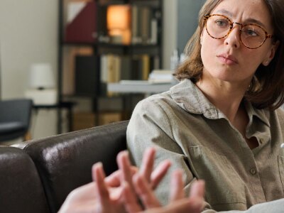 Two women sitting on couch discussing treatment plan during counseling session in cozy office.