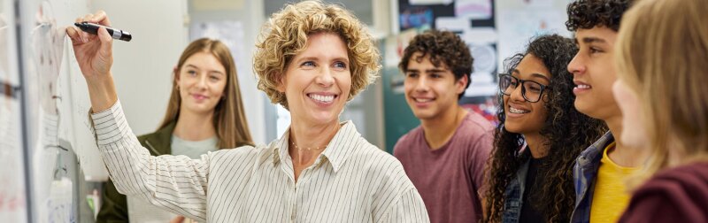 Smiling high school teacher teaching to class.