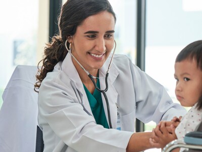 Young female doctor examines a young boy being held by his mother in a clinic