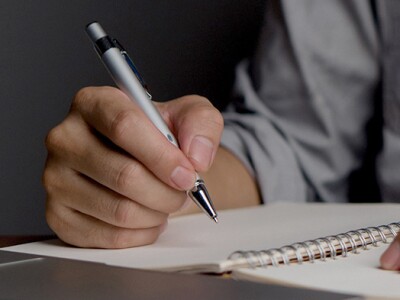 Man holding a pen and writing his to-do list in a note book