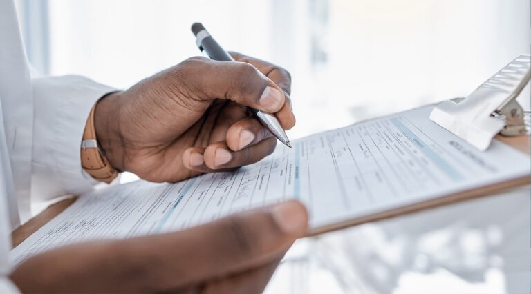 Hands of doctor filling out a form on a clipboard
