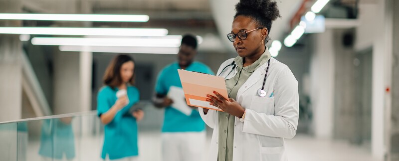 Female doctor reviewing medical documents in hospital corridor
