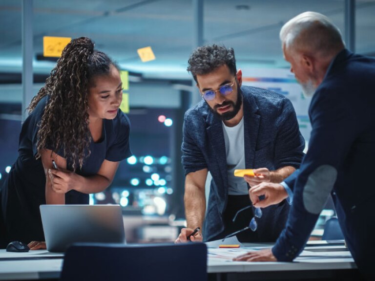 A diverse team of executives discuss financial investments during a night meeting.