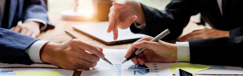 Financial analyst analysis business financial report on digital tablet during discussion at meeting.