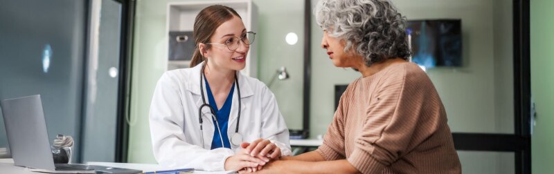 Female counselor sits at her desk providing mental health therapy and comfort to her female patient