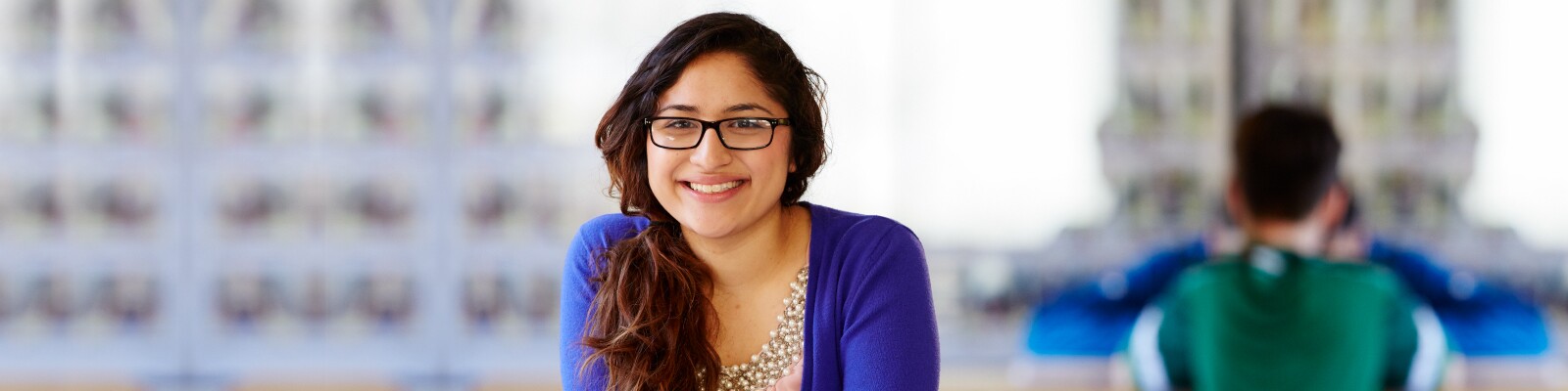 Marquette graduate student smiling while wearing a blue sweater and pearls