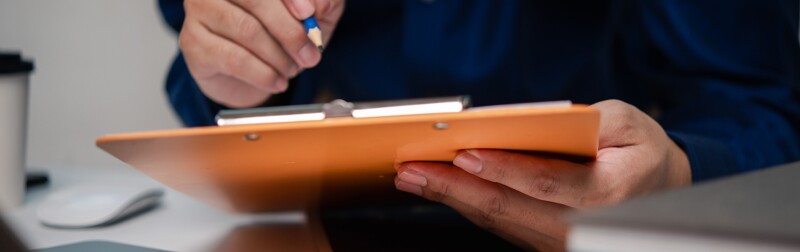 Man holding clipboard at desk