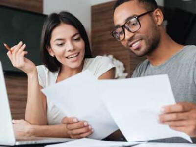 Two graduate students discussing information on paper and on a laptop screen