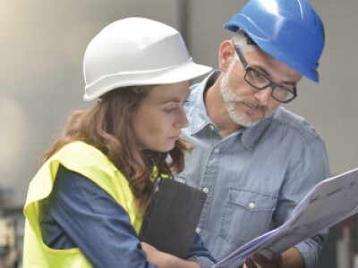 man and woman wearing hardhats looking at chart