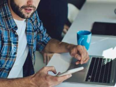 cybersecurity professional works on laptop and phone