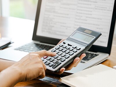 Accountant calculating net income formula at desk with calculator