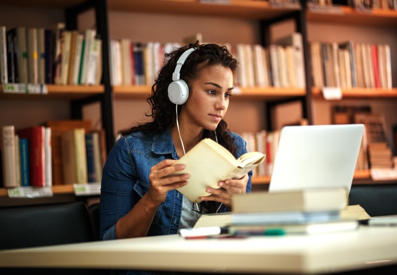 Young female student in library learning online