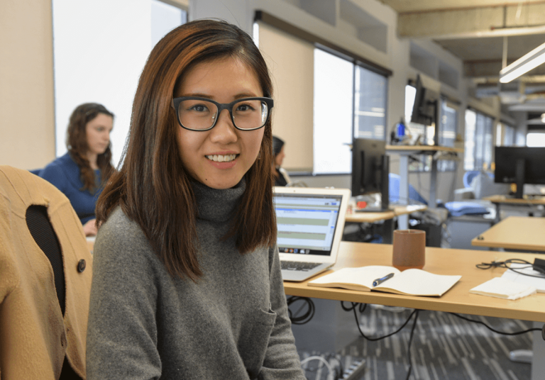 Woman in glasses working at desk on laptop