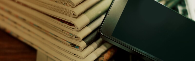 Stack of newspapers with a smart phone laying on them