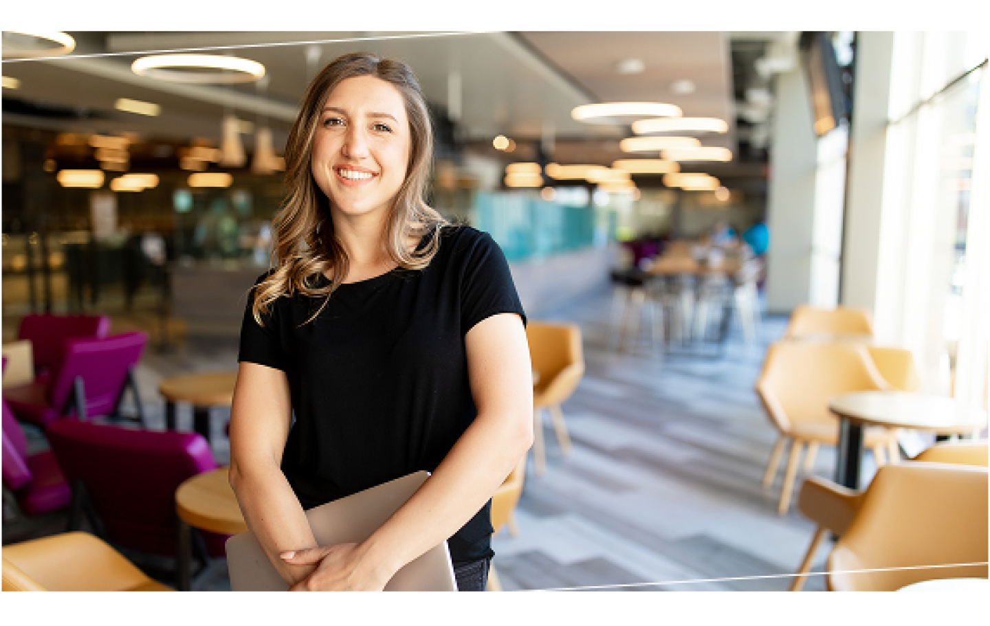 woman with a laptop standing in a common area