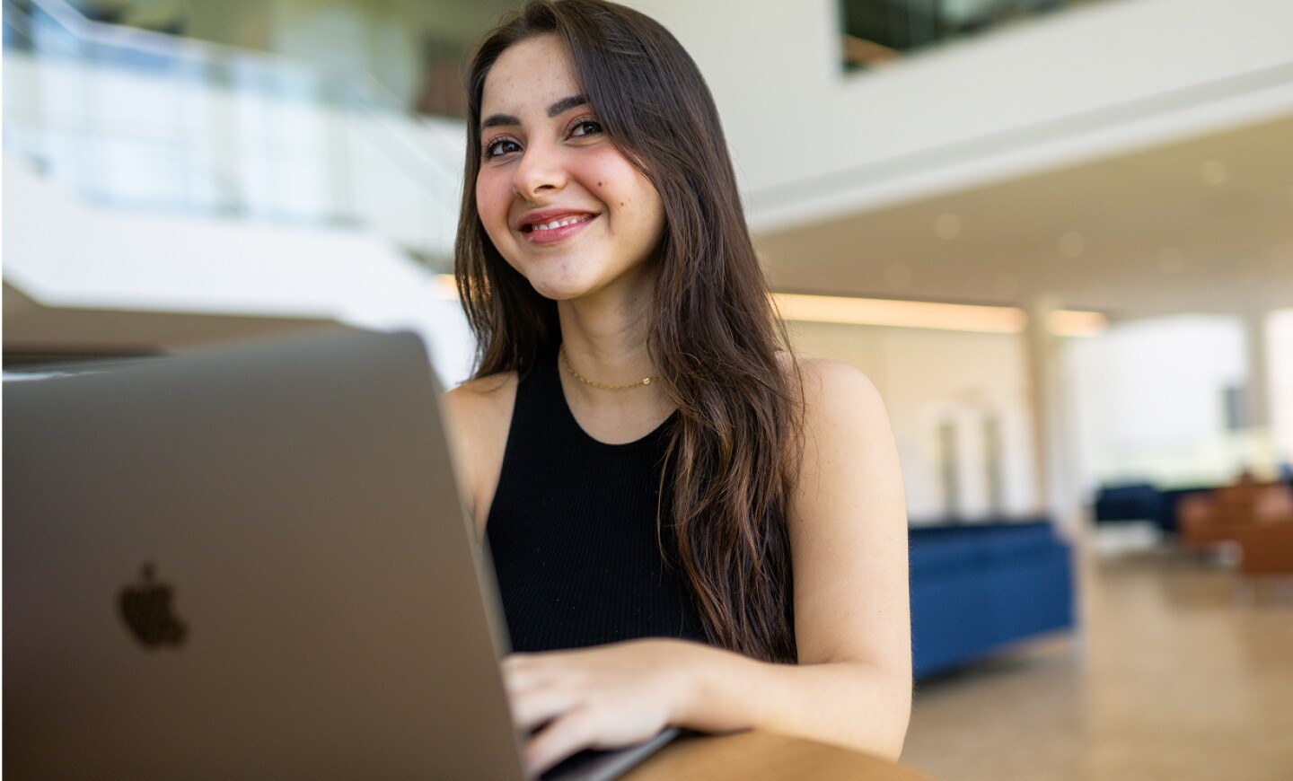 Smiling female Kent State student working on her laptop