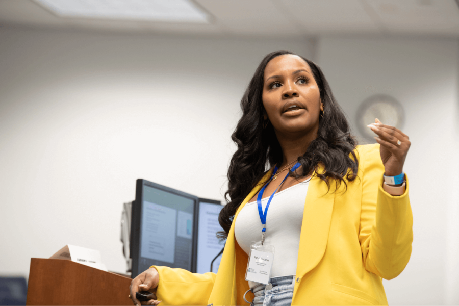 Woman in yellow coat presenting at a podium