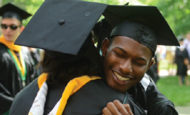 african american couple in graduation gowns hugging