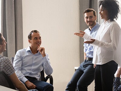 Smiling Black woman speaking at diverse corporate group meeting