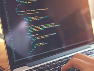 Closeup view of two hands typing code into a laptop