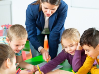 A teacher working with a group of young students to create a growth mindset classroom atmosphere.