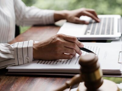 a person sitting at a desk with a laptop and clipboard next to a gavel