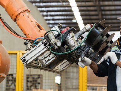 man working on robotic arm for manufacturing