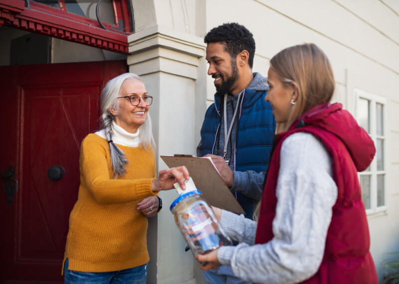 Two fundraisers canvas a woman at her door step for her support