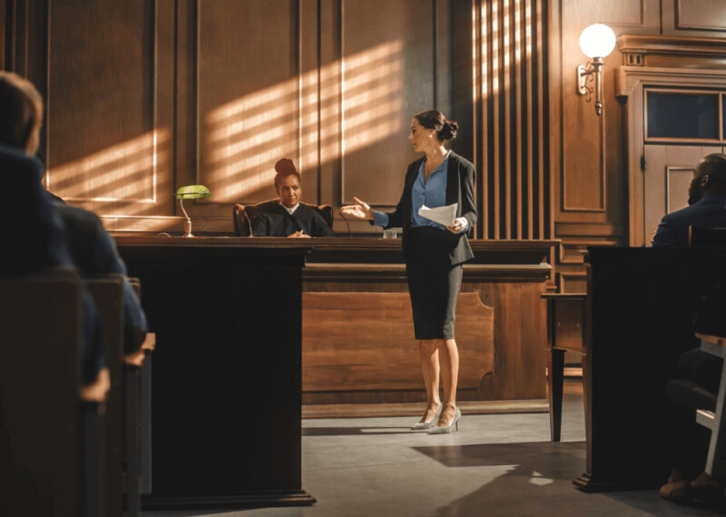 A female prosecutor presenting a case to a judge and jury