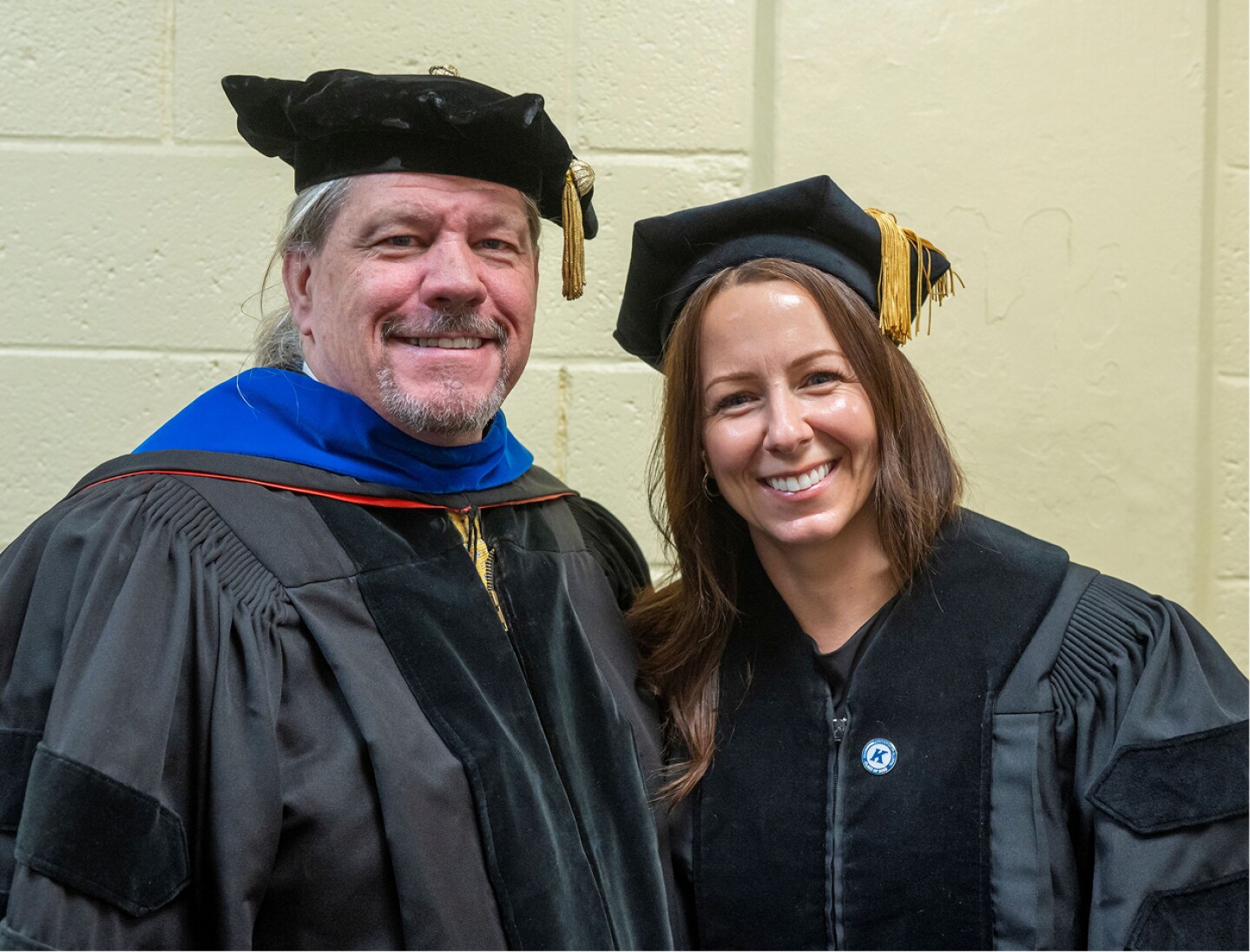 Kent State faculty member and student posing in graduation caps and gowns